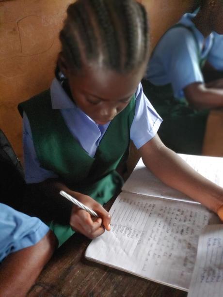 Dougbe River Presbyterian  student in a class writing a not